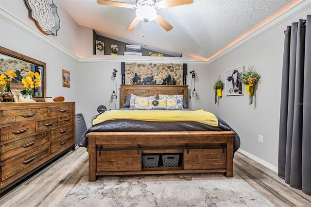 bedroom with ceiling fan, vaulted ceiling, a textured ceiling, and light hardwood / wood-style flooring