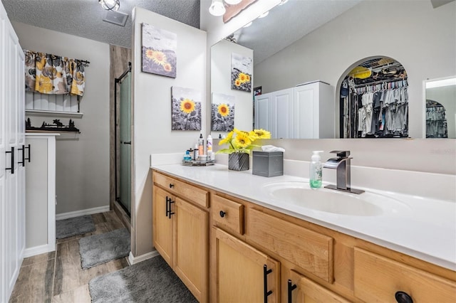 bathroom with a textured ceiling, a shower with door, and vanity