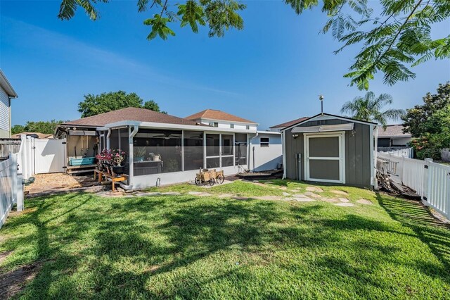 back of property with a sunroom, a storage unit, and a yard