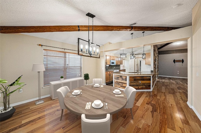 dining room featuring lofted ceiling with beams, a textured ceiling, baseboards, and wood finished floors