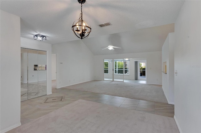 carpeted empty room featuring a textured ceiling, vaulted ceiling, and ceiling fan with notable chandelier