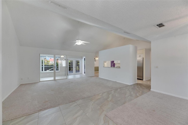 unfurnished living room featuring ceiling fan, light colored carpet, vaulted ceiling, french doors, and a textured ceiling