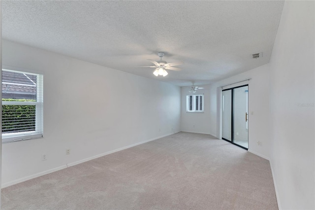 carpeted spare room featuring ceiling fan and a textured ceiling