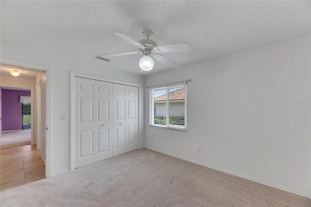 unfurnished bedroom with ceiling fan, a closet, carpet, and a textured ceiling