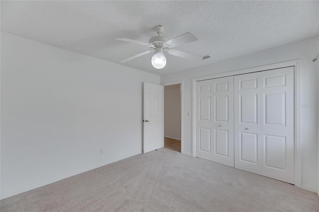 unfurnished bedroom with a textured ceiling, a closet, ceiling fan, and light carpet