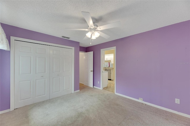 unfurnished bedroom with light colored carpet, a closet, a textured ceiling, and ceiling fan