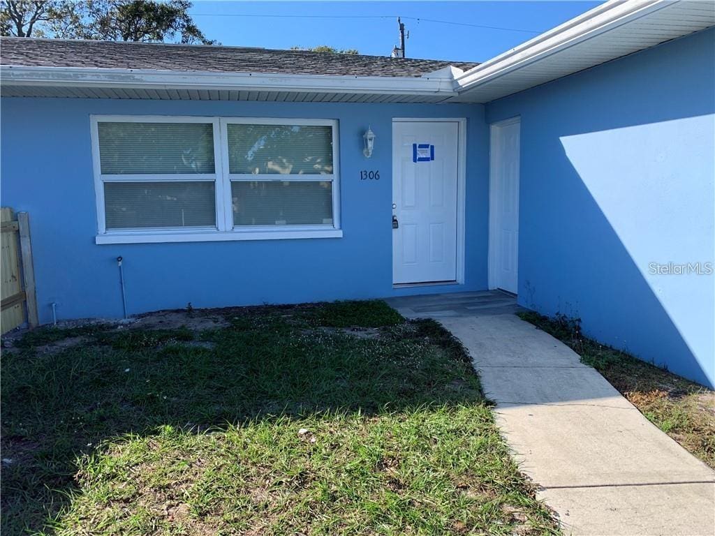 view of exterior entry with a lawn