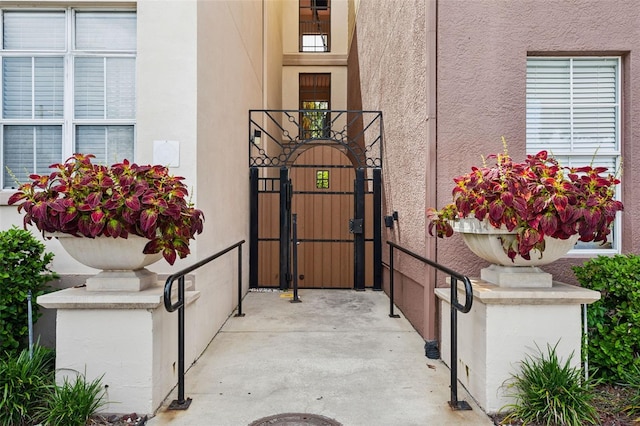 property entrance with stucco siding and a gate