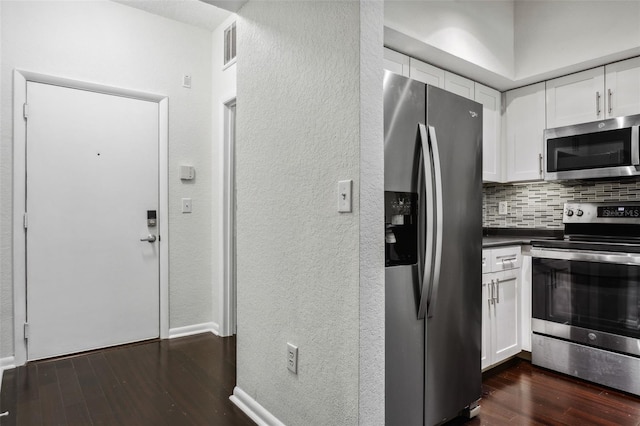 kitchen with stainless steel appliances, white cabinets, backsplash, a textured wall, and dark wood-style floors