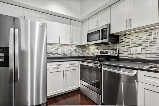 kitchen with tasteful backsplash, white cabinets, dark hardwood / wood-style flooring, and stainless steel appliances