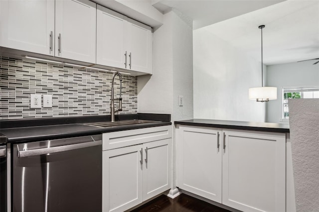 kitchen featuring stainless steel dishwasher, a sink, white cabinetry, backsplash, and dark countertops