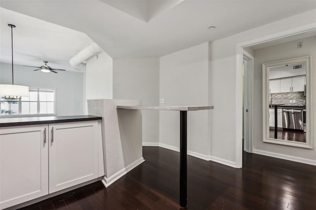 interior space with dark wood finished floors, ceiling fan, decorative backsplash, stainless steel dishwasher, and baseboards
