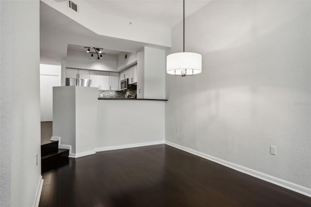 interior space with baseboards, stairway, track lighting, and dark wood-type flooring