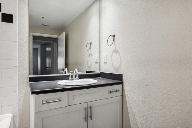 bathroom featuring vanity, a textured wall, and visible vents