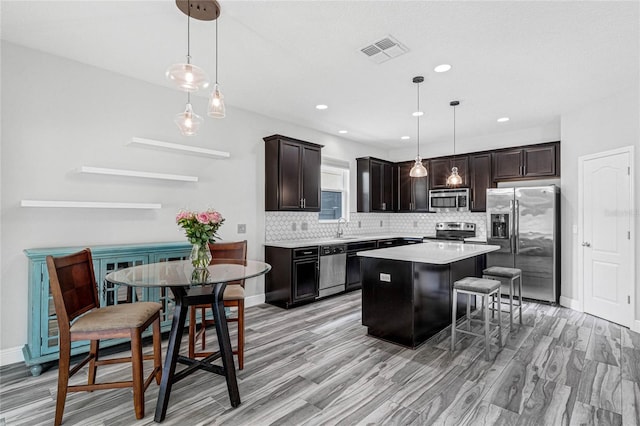 kitchen with pendant lighting, stainless steel appliances, backsplash, a center island, and sink