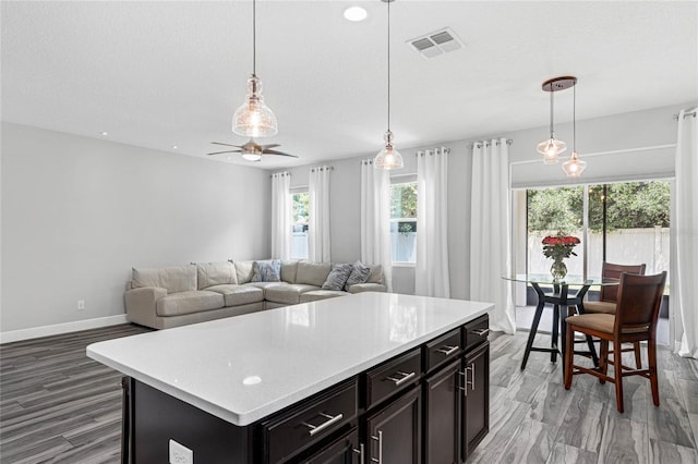 kitchen featuring a center island, wood-type flooring, hanging light fixtures, and ceiling fan