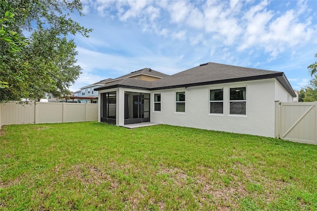 back of property featuring a sunroom and a lawn