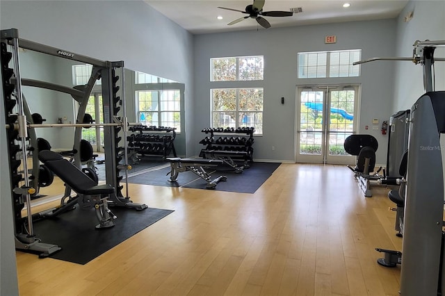 workout area featuring a towering ceiling, ceiling fan, and light hardwood / wood-style floors