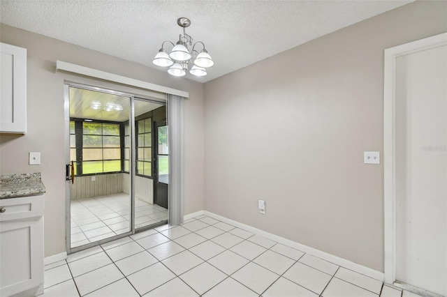 unfurnished dining area with a chandelier, a textured ceiling, and light tile patterned flooring