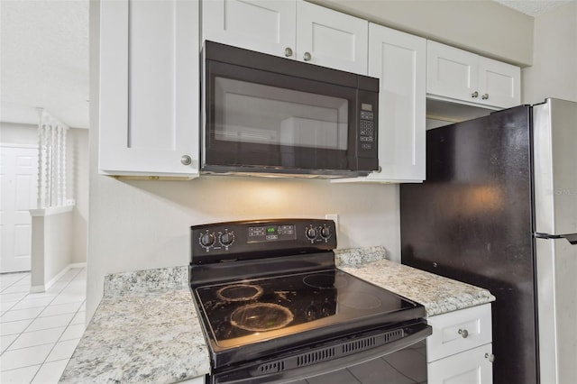 kitchen with white cabinets, black appliances, light tile patterned floors, and light stone counters