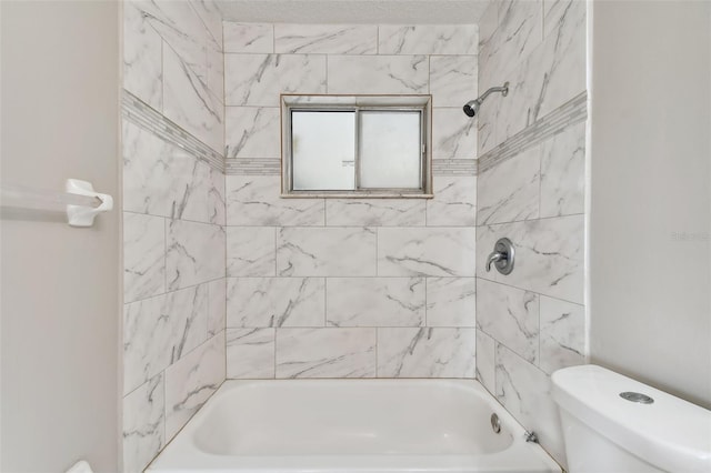 bathroom with tiled shower / bath combo and toilet