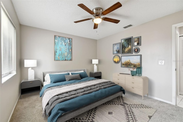 bedroom featuring a textured ceiling, light colored carpet, and ceiling fan