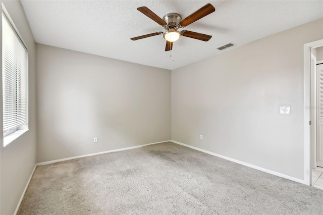 spare room with ceiling fan, a textured ceiling, and light colored carpet