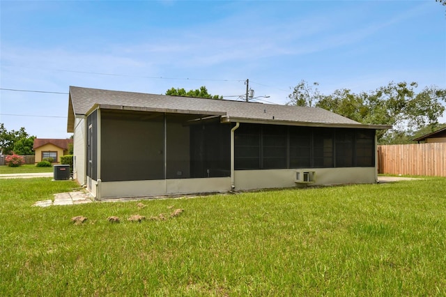 rear view of property with central AC unit, a sunroom, and a yard