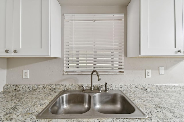 kitchen featuring white cabinetry, sink, and light stone counters