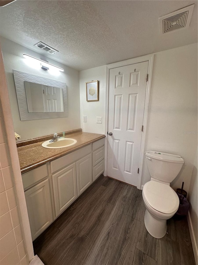 bathroom with wood-type flooring, toilet, a textured ceiling, and vanity