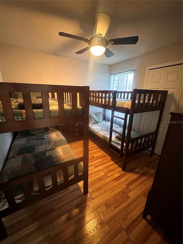 bedroom with wood-type flooring, a textured ceiling, and ceiling fan