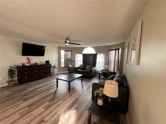 living room with a textured ceiling, ceiling fan, and hardwood / wood-style floors