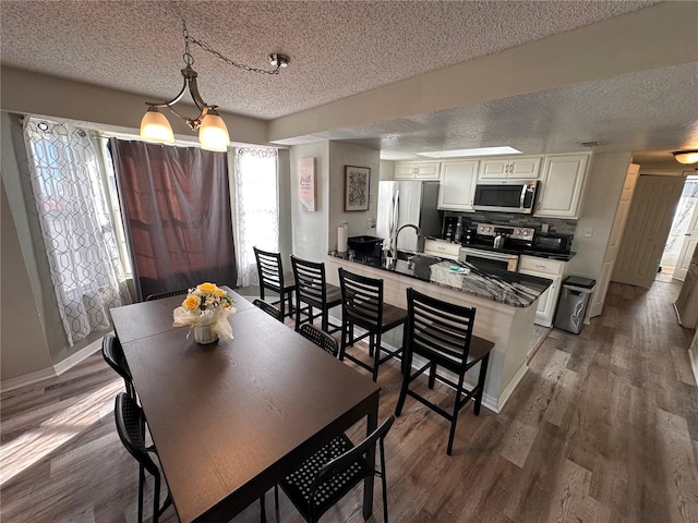 dining area with sink, dark hardwood / wood-style flooring, and a textured ceiling