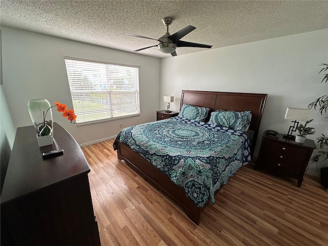 bedroom with wood-type flooring, a textured ceiling, and ceiling fan