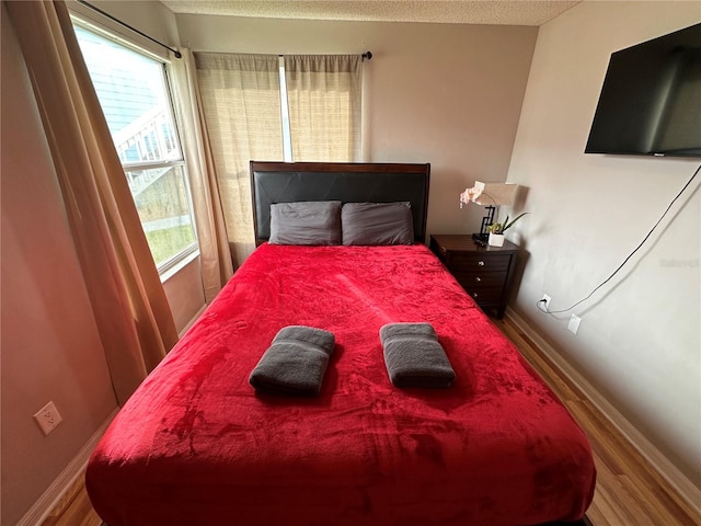 bedroom with multiple windows and hardwood / wood-style flooring