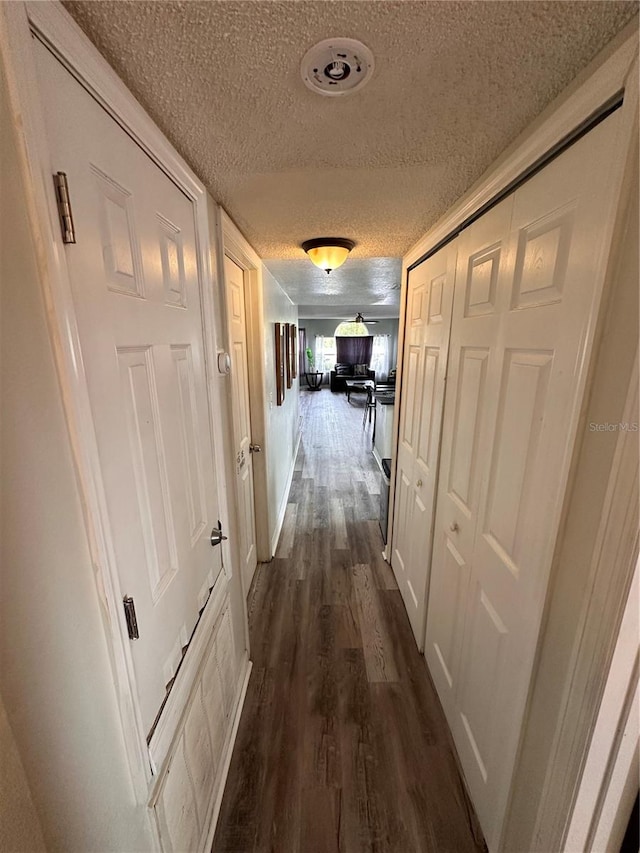 hall featuring dark wood-type flooring and a textured ceiling