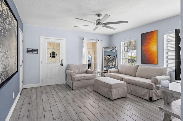 living room featuring a textured ceiling, ceiling fan, and light hardwood / wood-style flooring