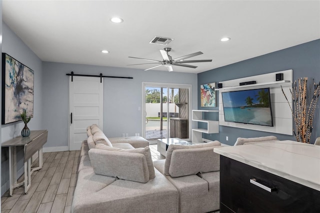 living room featuring light hardwood / wood-style floors, ceiling fan, and a barn door