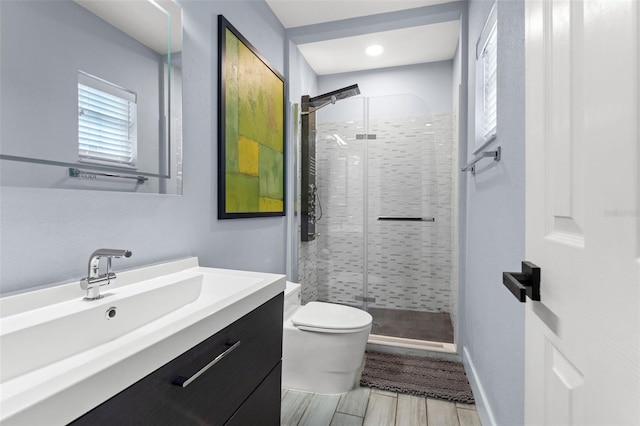 bathroom with hardwood / wood-style flooring, a shower with door, vanity, and toilet