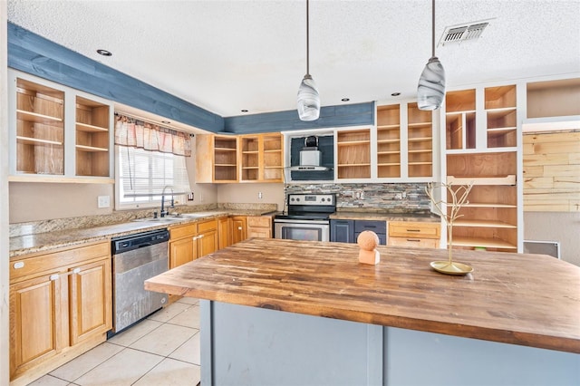 kitchen with decorative light fixtures, appliances with stainless steel finishes, butcher block counters, a textured ceiling, and light tile patterned floors