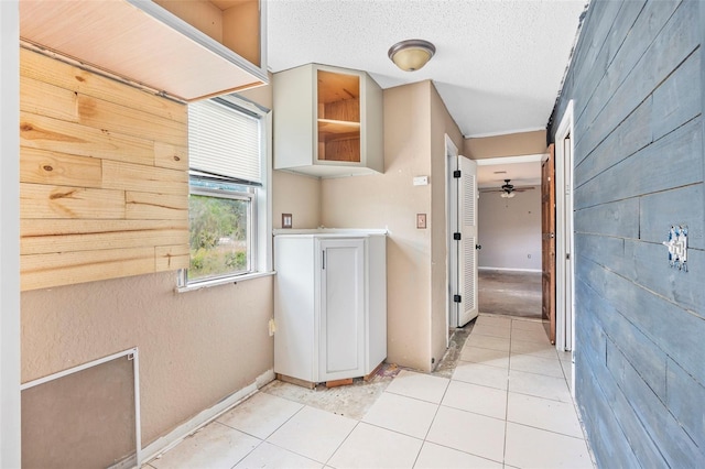 laundry area with ceiling fan, light tile patterned floors, and a textured ceiling