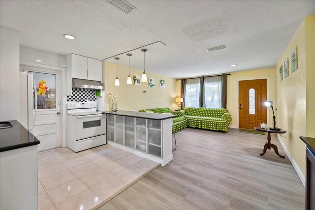 kitchen with light wood-type flooring, decorative backsplash, white cabinets, a textured ceiling, and white appliances