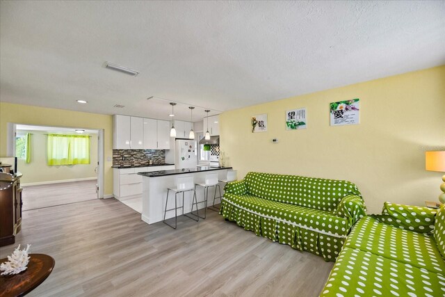 living room with a textured ceiling, rail lighting, and light wood-type flooring