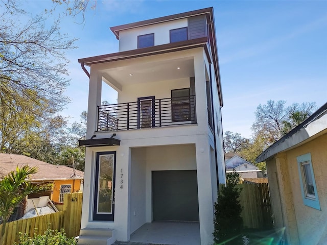 contemporary home with a balcony, fence, and stucco siding