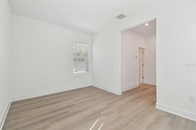 unfurnished room featuring light wood-type flooring, baseboards, and visible vents