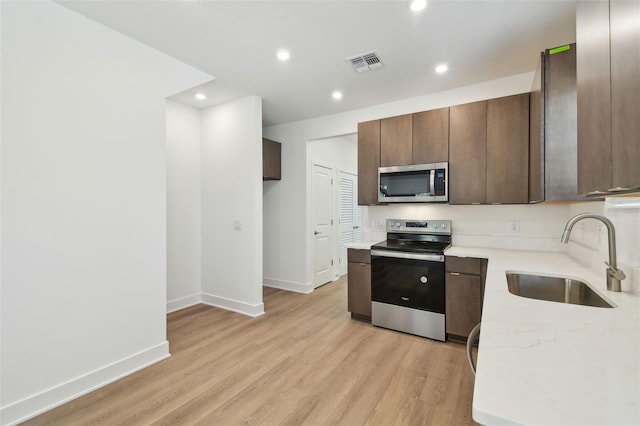 kitchen featuring recessed lighting, stainless steel appliances, a sink, visible vents, and light wood finished floors