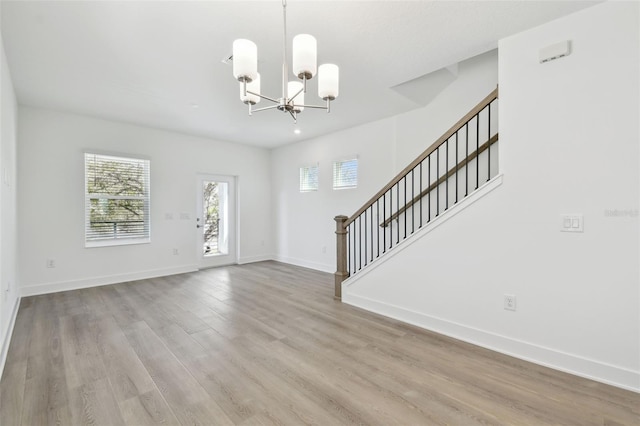 foyer entrance featuring stairs, a chandelier, baseboards, and wood finished floors