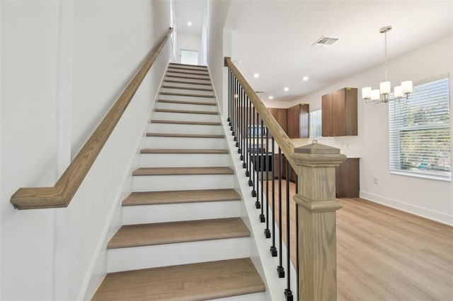 staircase featuring a notable chandelier, recessed lighting, wood finished floors, visible vents, and baseboards