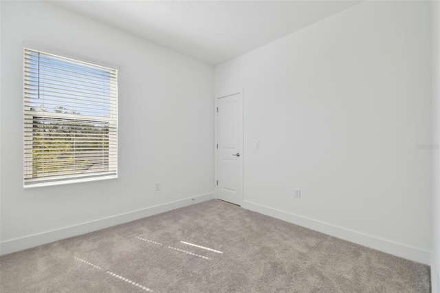 carpeted empty room featuring baseboards