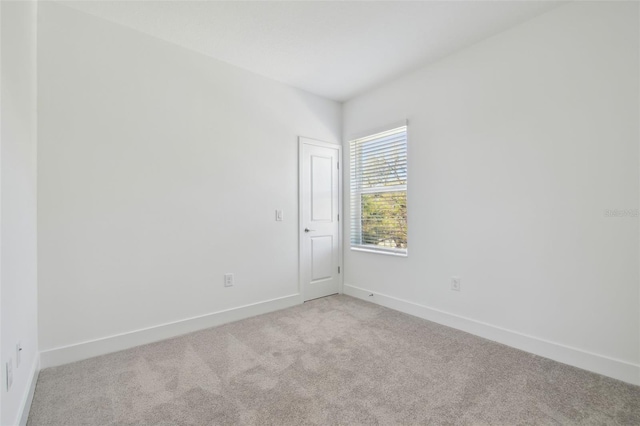 unfurnished room featuring baseboards and light colored carpet